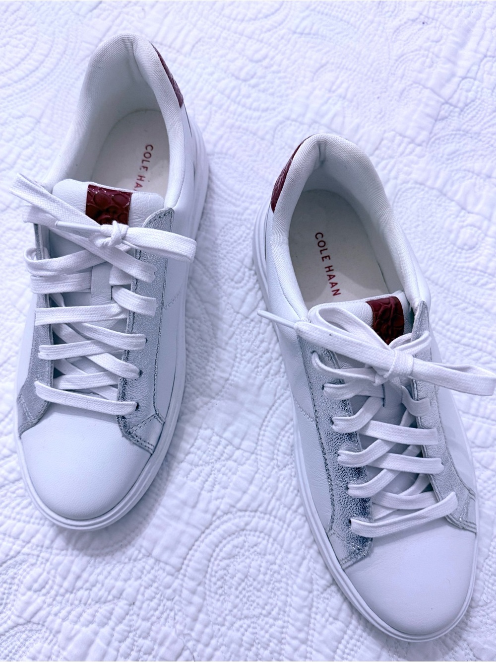 White Cole Haan sneakers featuring silver metallic accents and red heel detail